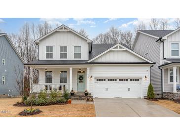 Charming two-story home with white siding, a covered porch, and a two-car garage, creating a welcoming curb appeal at 349 Shadow Falls Dr, Wendell, NC 27591