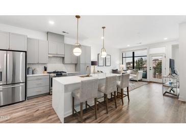 Open concept kitchen featuring gray cabinets, stainless steel appliances, and a large center island with seating at 615 Daniels St # 318, Raleigh, NC 27605
