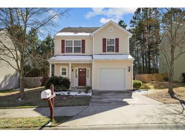 Charming two-story home with a well-manicured front yard, attached garage and red shutters at 813 Woodside Park Ln, Durham, NC 27704