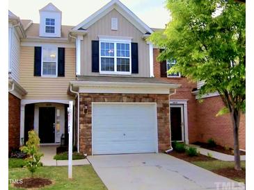 Charming townhome featuring a stone facade, attached garage, and well-maintained lawn at 8329 Pilots View Dr, Raleigh, NC 27617