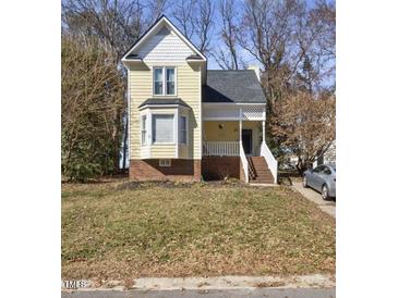 Charming yellow home features a welcoming porch, bay window, and well-maintained front yard at 1721 Kingston Heath Way, Raleigh, NC 27604