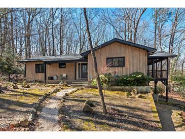 Charming single-story home featuring wood siding, dark trim, and landscaped front yard surrounded by mature trees at 2107 Markham Dr, Chapel Hill, NC 27514