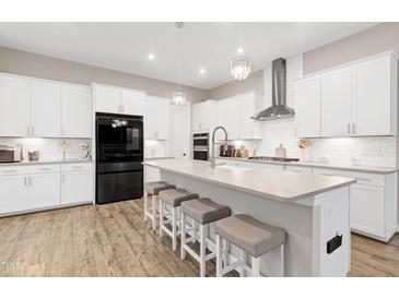 Modern kitchen featuring white cabinetry, a large island with seating, and stainless steel appliances at 213 W Weatherford Dr, Angier, NC 27501