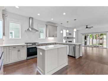 Bright kitchen featuring an island, modern stainless steel appliances, and seamless access to the living room with fireplace at 5 Bart St, Raleigh, NC 27610