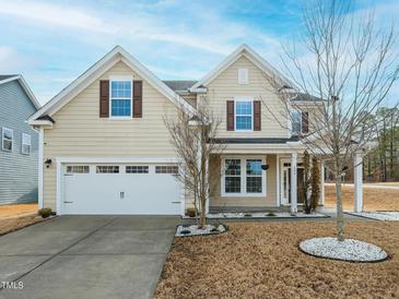 Charming home featuring a two-car garage, a well-manicured lawn, and a welcoming front porch at 800 Tree Green Ln, Wake Forest, NC 27587