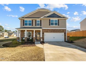 Charming two-story home featuring a stone facade, covered porch, and a two-car garage at 1020 Broadlands Way, Graham, NC 27253
