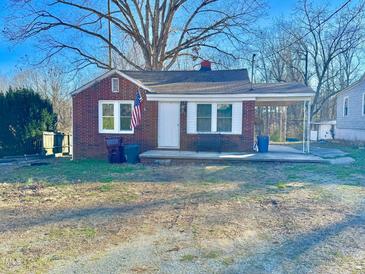 Charming one-story brick home featuring a covered carport and an American flag at 1043 Cavel Chub Lake Rd, Roxboro, NC 27574