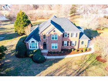 Aerial shot of a brick two-story home, showcasing landscaping and a nearby pond at 10620 Staghound Trl, Zebulon, NC 27597