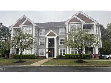View of the gray home exterior showcasing mature trees, manicured lawns, and multiple window views at 1828 Parkside Village Dr, Clayton, NC 27520