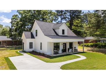 Charming two-story white home featuring a welcoming front porch and freshly manicured lawn at 412 N Green St, Selma, NC 27576