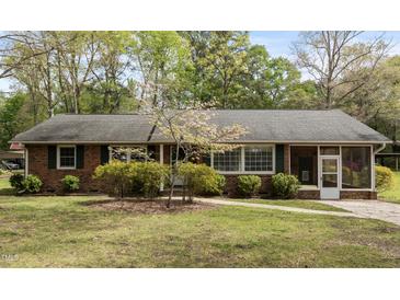 Charming brick home features manicured landscaping, a well-maintained lawn, and an inviting screened-in porch at 714 W J St, Erwin, NC 28339