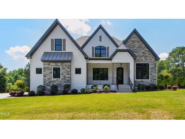 Beautiful new construction home with a manicured lawn, stone accents, and a welcoming front porch at 8621 Bishop Pine Ln, Wake Forest, NC 27587