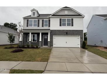 Two story home with a brick and siding exterior, attached garage, and well maintained front lawn at 139 Ethel Ln, Angier, NC 27501