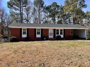 Charming one-story brick home with an attached carport and well-maintained front yard and established trees at 613 Sexton Ave, Zebulon, NC 27597
