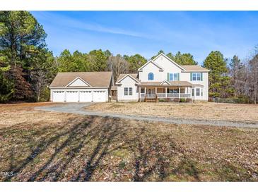 Inviting two-story home featuring a spacious front porch and a detached three-car garage on expansive lot at 1175 Faulkner Town Rd, Henderson, NC 27537