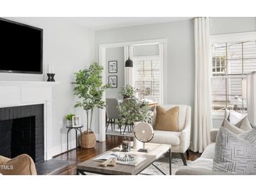 Bright living room featuring a fireplace, stylish decor, and an open view to the dining area at 2204 Guess Rd, Durham, NC 27705