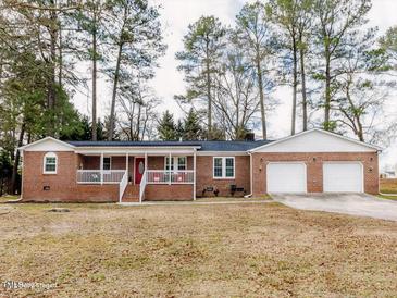 Charming red brick home with white picket fence and a two-car garage surrounded by mature trees at 4704 Upchurch Ln, Wake Forest, NC 27587