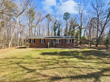 Charming brick ranch-style home with a well-manicured front yard and a covered carport at 5614 Greenbay Dr, Durham, NC 27712