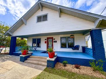 Charming two-story home with a blue-painted porch, swing, and manicured landscaping at 709 North St, Durham, NC 27701