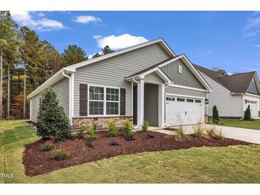 Charming single-story home boasts manicured landscaping, stone accents, and an attached garage at 208 Brickwell Way, Youngsville, NC 27596
