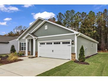 Charming single-Gathering home featuring a two-car garage, light green vinyl siding, and a well-maintained front yard at 305 Brickwell Way, Youngsville, NC 27596