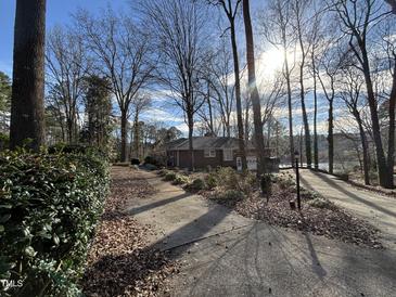 Charming brick home featuring a well-maintained yard with mature trees on a sunny day at , Raleigh, NC 27613