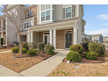 Inviting townhome exterior featuring brick accents, neutral siding, and a charming front porch with column supports at 2959 Sunflower Rd, Apex, NC 27502