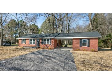 Charming red brick home featuring a gravel driveway, covered carport, and nicely trimmed landscaping at 3639 Nc Highway 39, Selma, NC 27576