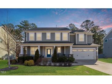 Charming two-story home features a covered front porch, manicured lawn, and attached two-car garage at 401 River Falls Dr, Apex, NC 27539
