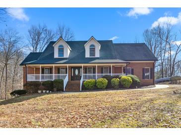 Charming brick home with a welcoming front porch and dormer windows under a clear blue sky at 4639 Reid Rd, Elon, NC 27244