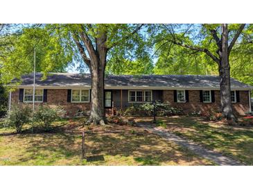 Charming brick home with a landscaped front yard, mature trees, and a welcoming entrance at 610 Westbrook Dr, Burlington, NC 27215