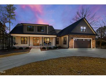Charming home with stone accents, a two-car garage, and a welcoming front porch at 79 Cove Lndg, Sanford, NC 27332