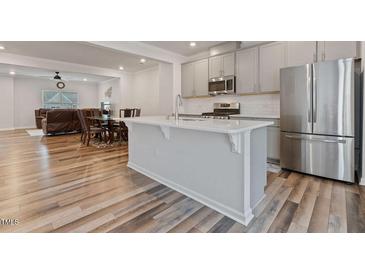 Bright kitchen features stainless steel appliances, granite countertops, and an open layout to the dining and living area at 1430 Rosepine Dr, Cary, NC 27519