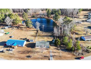 An aerial view of a property featuring a quaint house and a serene pond, surrounded by mature trees at 186 Sunrise Dr, Sanford, NC 27332