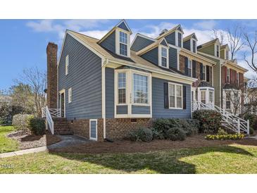 Charming townhome with blue siding, brick accents, manicured landscaping, and dormer windows at 2820 Bedfordshire Ct, Raleigh, NC 27604