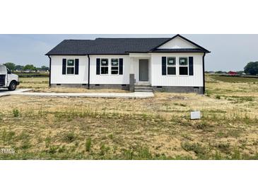 New construction features a white exterior, black shutters, and a well-manicured lawn at 73 Grace Pond Ave, Benson, NC 27504