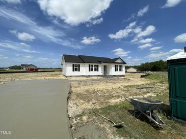 Newly built white single-story home with black shutters and roof under a blue sky with fluffy clouds at 73 Grace Pond Ave, Benson, NC 27504