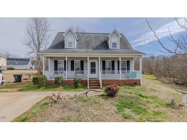 Charming home featuring a welcoming front porch, dormer windows, and a well-manicured lawn at 802 N Fifth St, Mebane, NC 27302