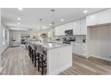 Bright kitchen features a large granite island with seating and modern appliances. Opens to living room at 1309 N Holland Rd, Fuquay Varina, NC 27526