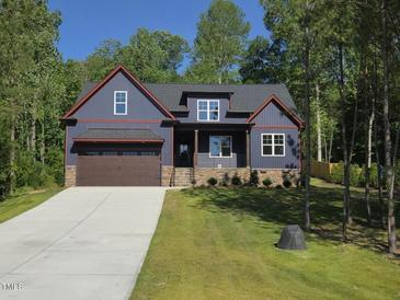 Charming two-story home with a beautiful dark-blue exterior, covered porch, and an attached two-car garage at 140 Pilot Ridge Rd, Zebulon, NC 27597
