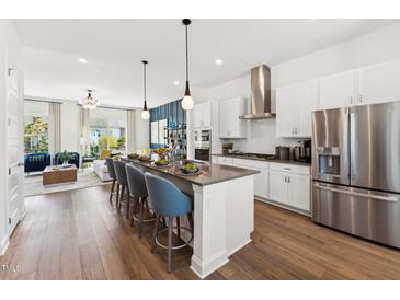 Open-concept kitchen featuring a large island with seating, stainless steel appliances, and wood flooring at 2800 Kempthone Rd # 65, Cary, NC 27519