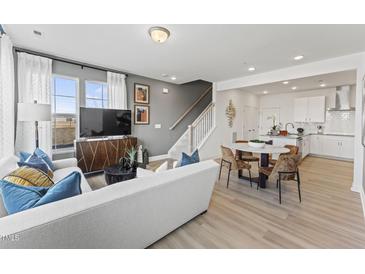 Bright open-concept living room featuring modern furnishings, large windows, and a stylish dining area adjacent to the kitchen at 10529 Pleasant Branch Dr # 101, Raleigh, NC 27614