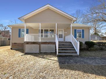 Charming home featuring a covered front porch with white railing and blue shutters, enhancing curb appeal at 207 Lawrence St, Fuquay Varina, NC 27526