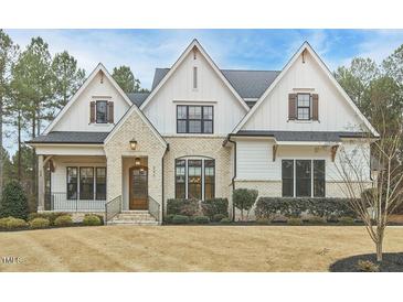 Charming two-story home with brick and white siding, gabled roof, manicured landscaping, and a welcoming front porch at 240 Seaforth Landing Dr, Pittsboro, NC 27312