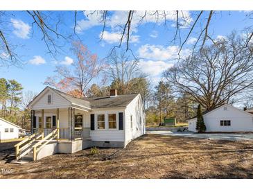 Charming home with a cozy front porch and white siding, complemented by a detached garage at 2504 E East Geer St, Durham, NC 27704