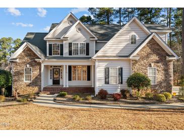 Charming two-story home with stone accents, manicured lawn, and inviting front porch at 2600 Buckingham Dr, Sanford, NC 27330