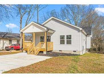 Charming single-story home featuring light gray siding, a welcoming front porch and manicured landscaping at 605 Lee St, Burlington, NC 27215