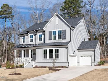 Charming two-story home featuring a manicured lawn, covered porch, and attached two car garage at 696 The Parks Dr, Pittsboro, NC 27312