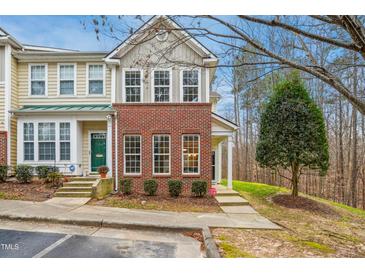 Charming two-story townhome featuring brick accents, a well-manicured lawn, and a welcoming green front door at 4555 Sugarbend Way, Raleigh, NC 27606