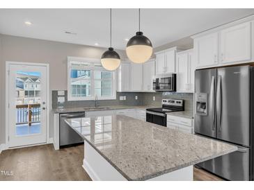 Bright kitchen with stainless appliances, white cabinets, granite countertops, and a center island at 507 Gateway Townes Blvd, Wake Forest, NC 27587